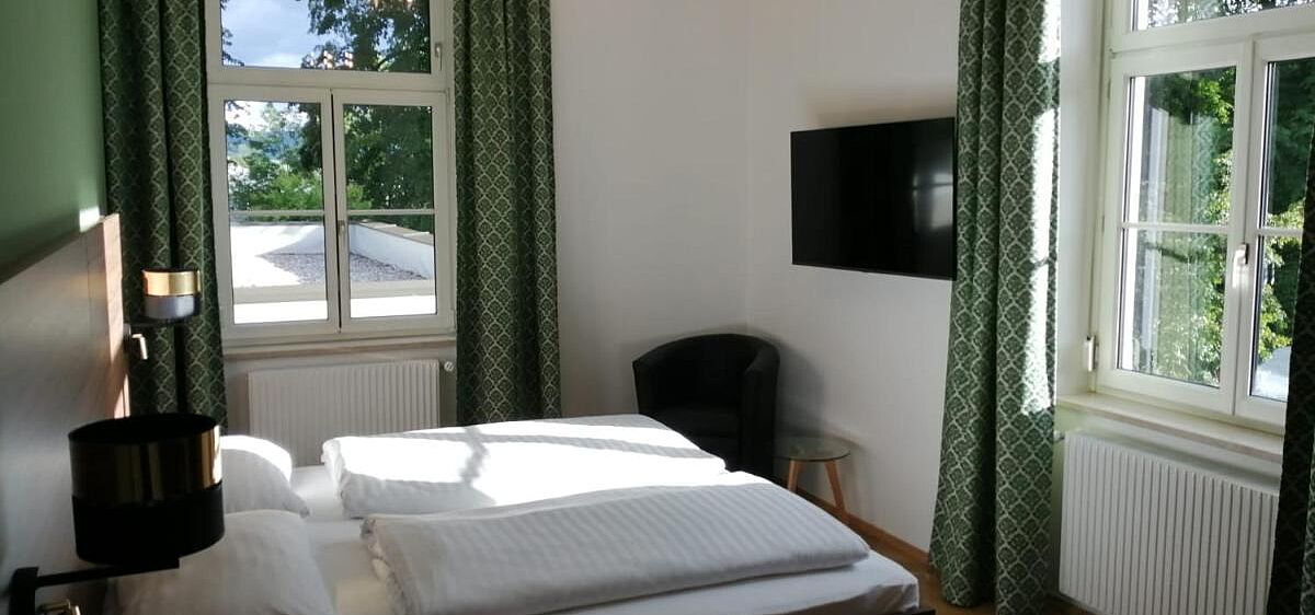 Bild zeigt Innenraum von Doppelzimmer mit Blick in den grünen Park im Glögglhof.